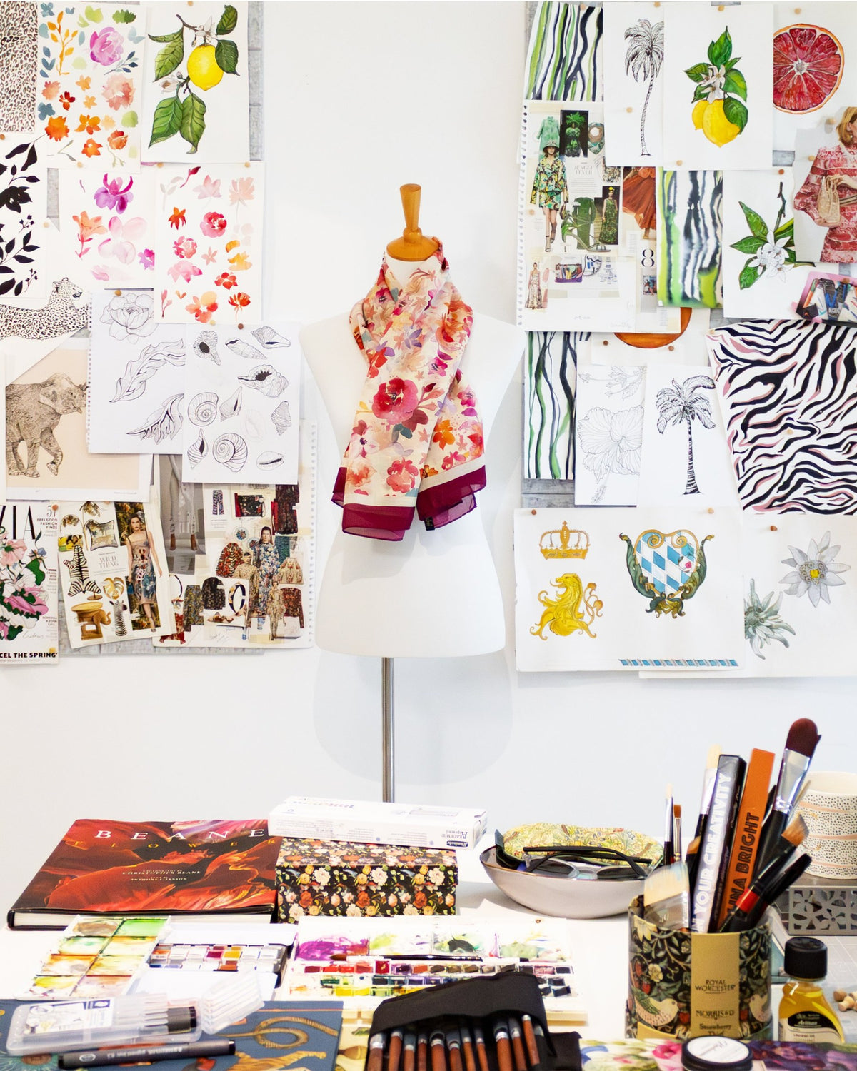 Moodboard im Atelier von Lamberty Munich mit Skizzen, Aquarellen und einem Seidenschal auf einer Schneiderbüste