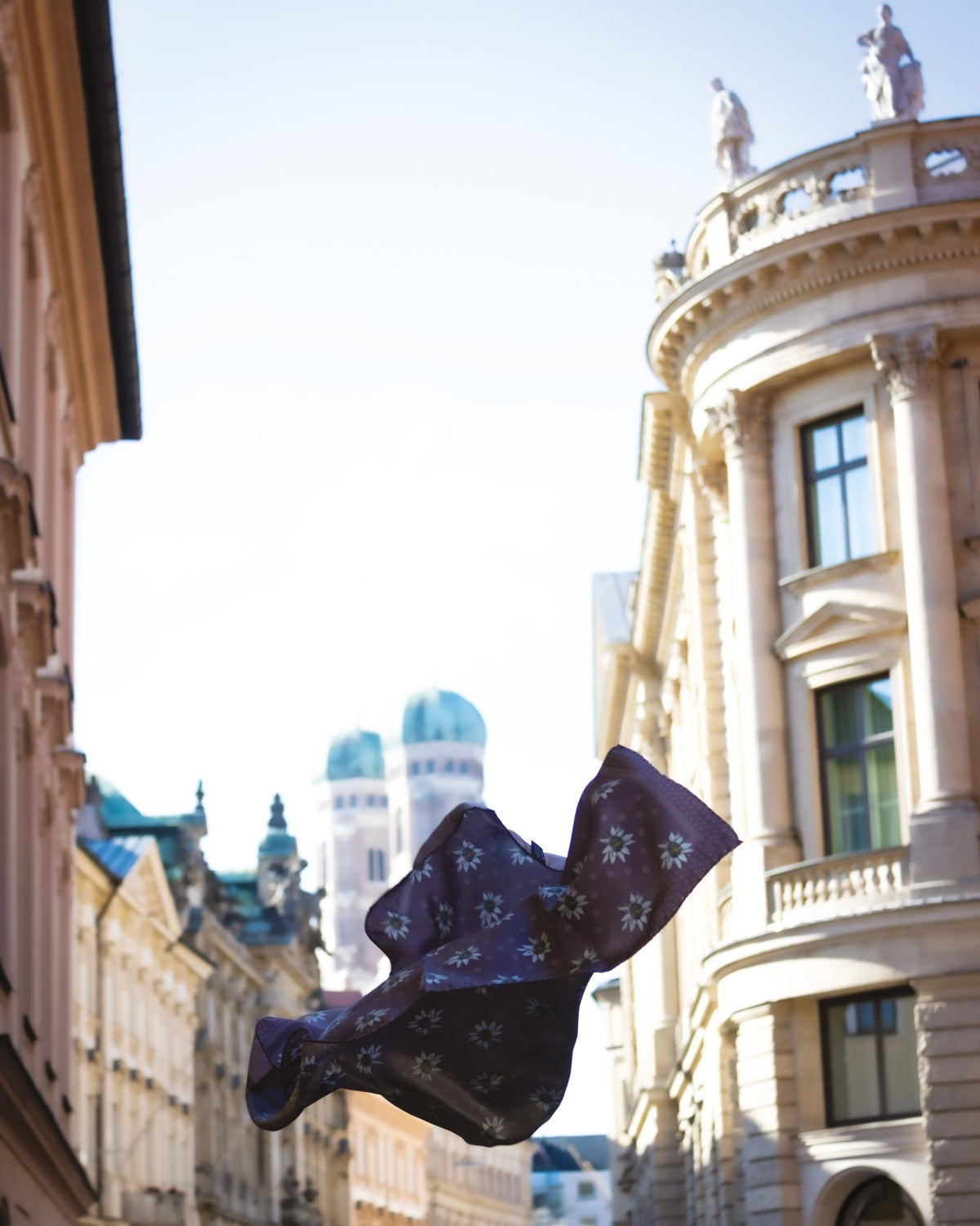 Seidenschal von Lamberty Munich mit Edelweißmotiv weht vor den Türmen der Münchner Frauenkirche